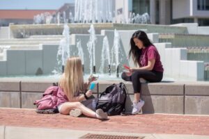 Two students studying at the fountain while holding popsicles