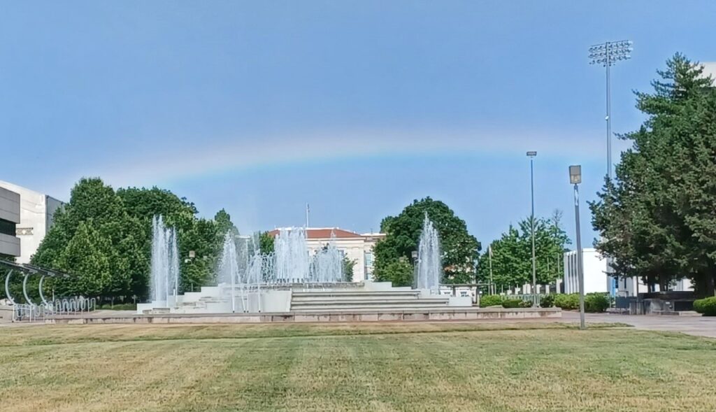 A summer scene of the Missouri State John Q Hammons Fountain with a rainbow.