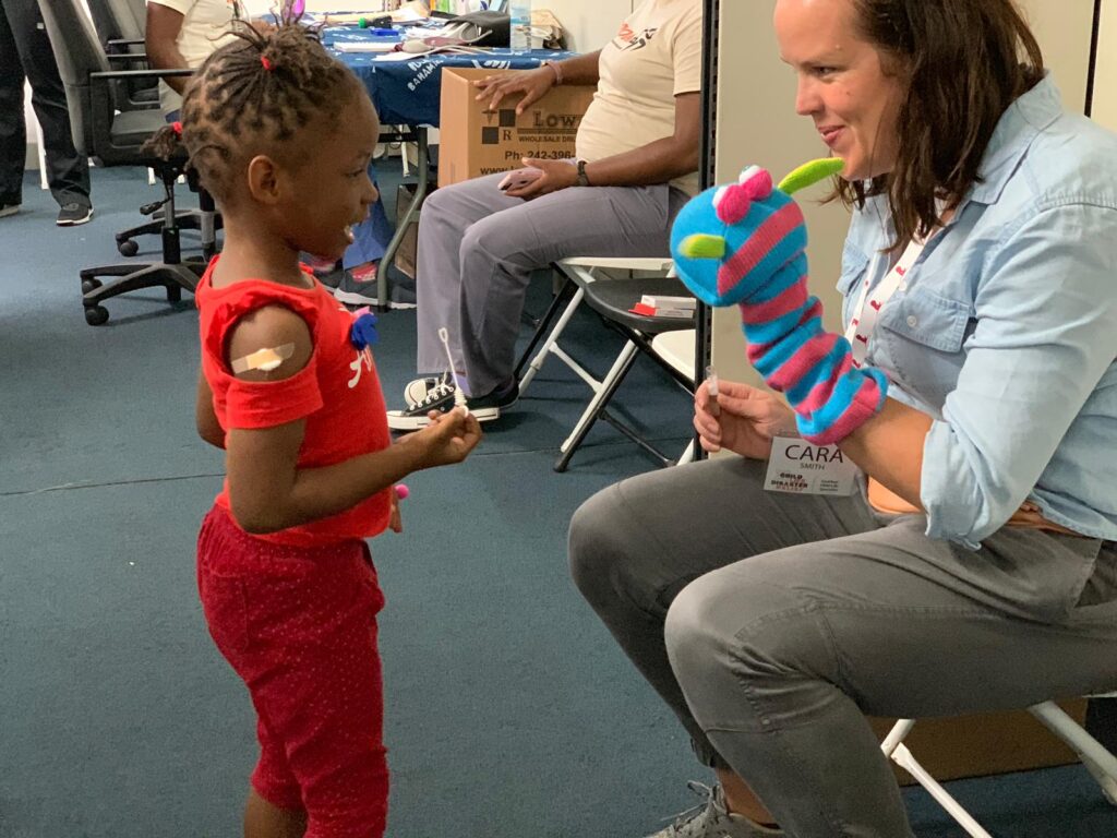 Cara Smith plays with puppets with a young girl