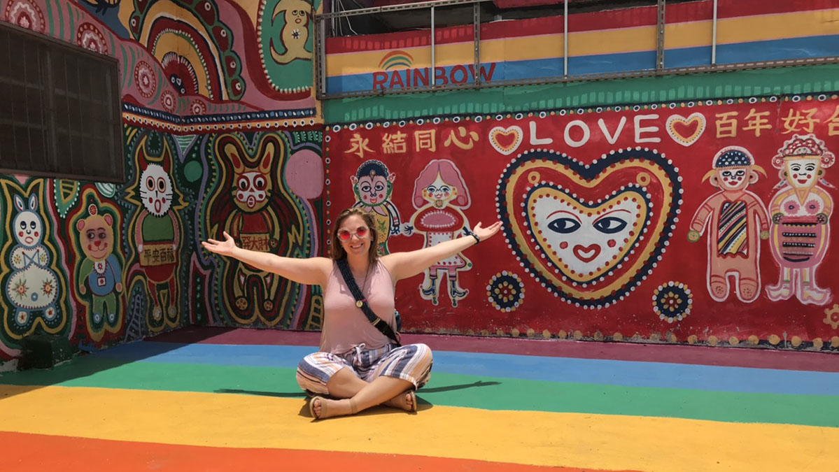 Kayla Gann sits in front of a colorful mural in Taiwan.