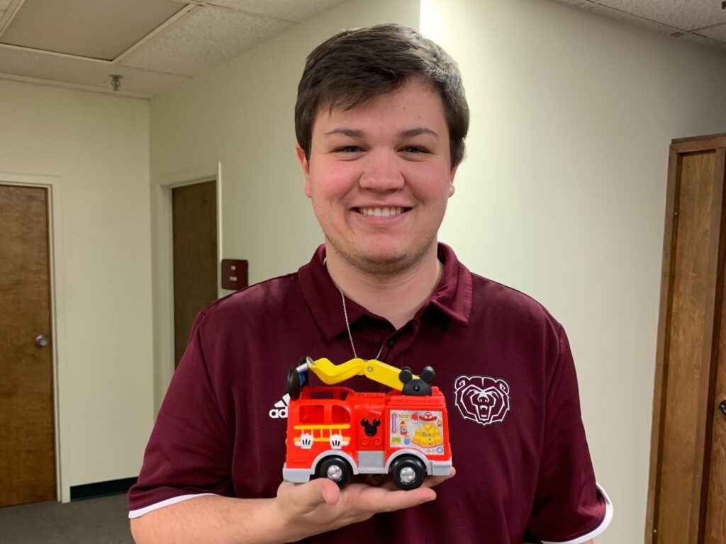 John Augustine holds a toy firetruck for students at the clinic.