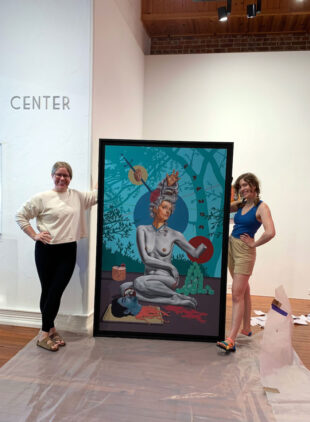 Two women standing next to large painting in art gallery
