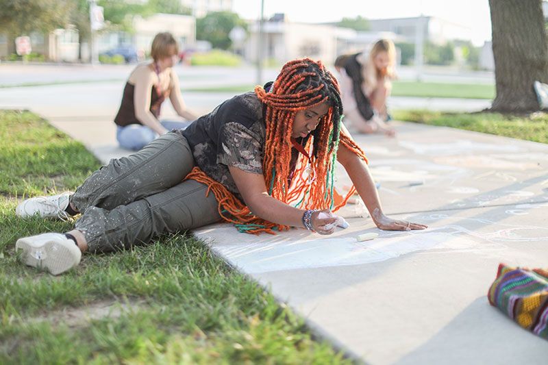 MFAA 2023 student draws with chalk on sidewalk