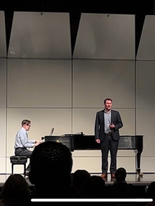Young man singing with older man playing piano