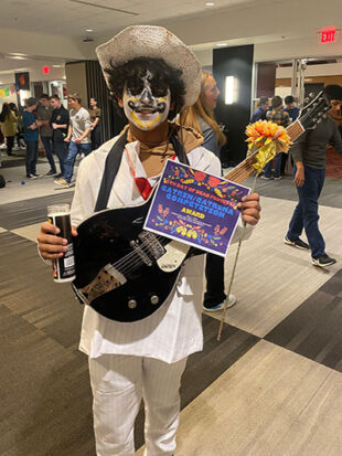 School age student dressed in Mexican Catrin costume with guitar