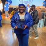 Student poses in front of Zeta Phi Beta Sorority shield.