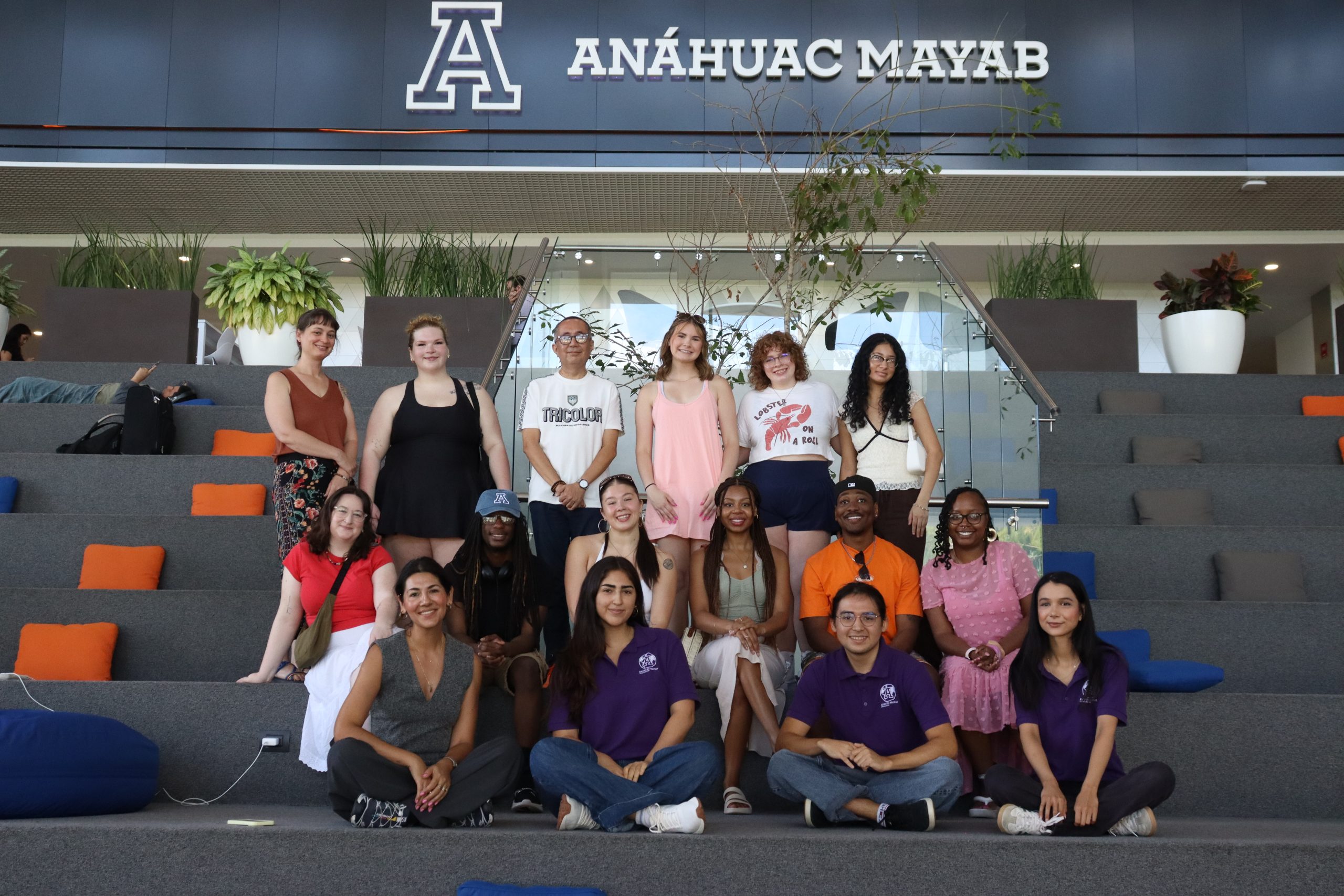 A group of students pose for a photo in front in front of a Anáhuac Mayab sign.