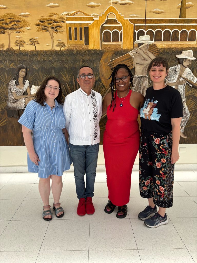 Members of the trip staff pose for a photo in front of a decorative backdrop.