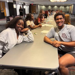 Two students sitting at a table smiling. 