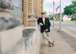 A young man posing against a brick wall.