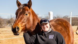 A photo of Sophia Karney standing next to a horse.