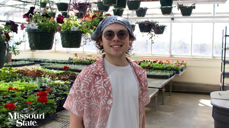 A smiling Zach Morris in a greenhouse.