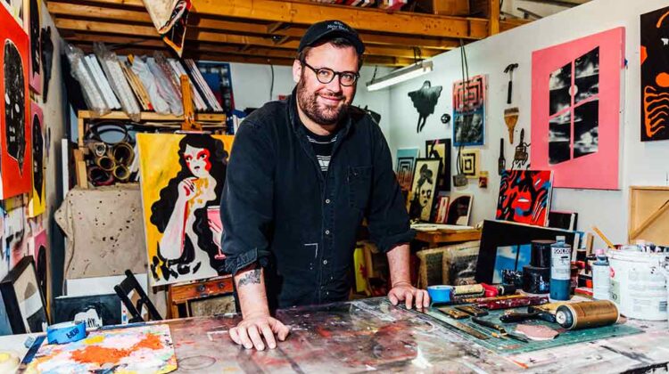 Daniel Zender in art studio with a collection of his work.
