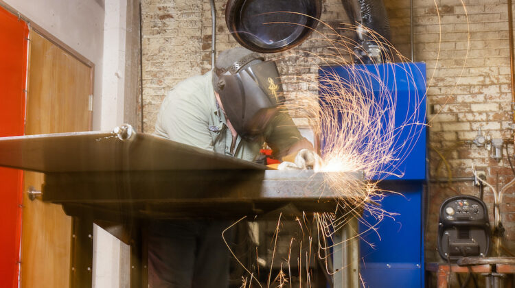 A sculptor creating sparks with tools in an industrial studio