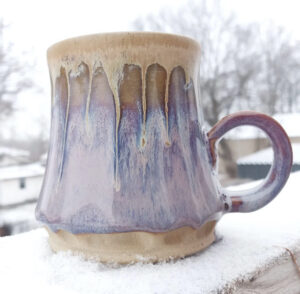 A handmade ceramic mug with iridescent purple glaze