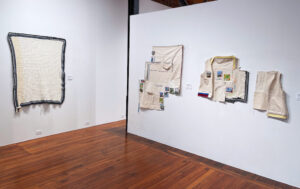 Hand-sewn art pieces hanging on a white gallery wall
