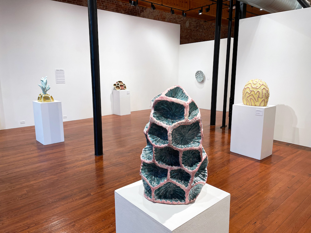 Large ceramic structures that mimic coral arranged on tall white pedestals