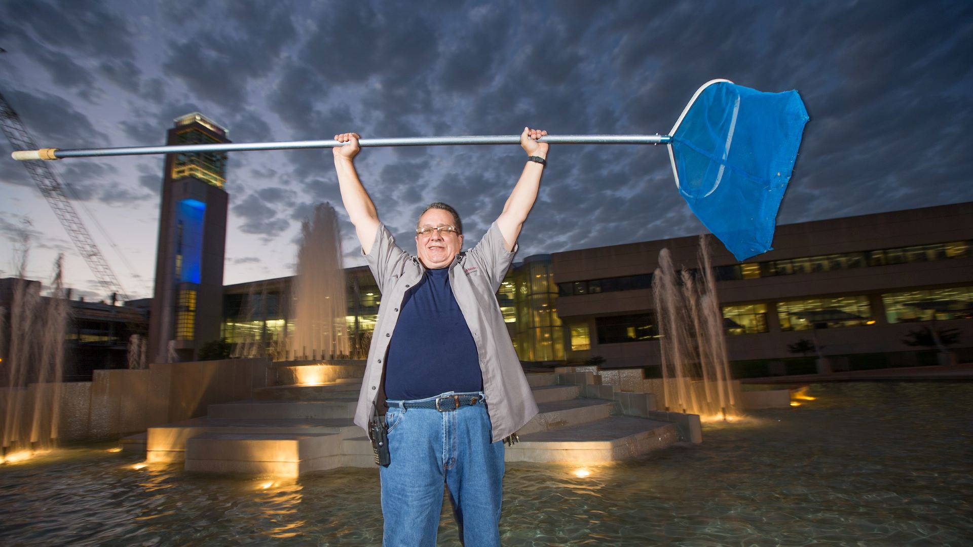 Leonard Haymans holds a pool net over his head at the John Q. Hammons Fountains.