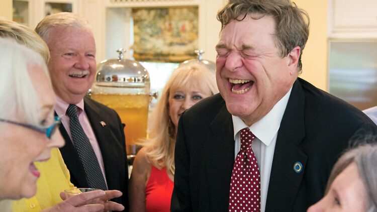 John Goodman laughs with guests during reception