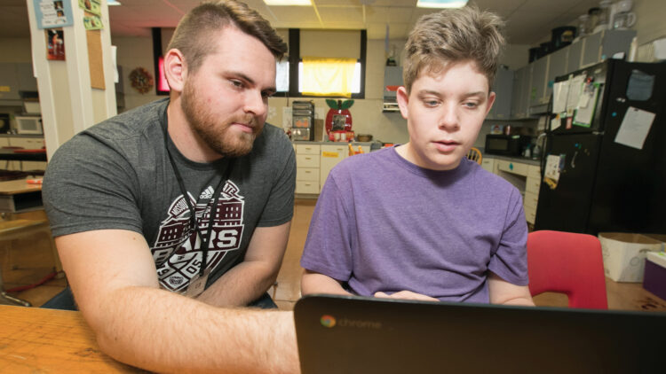 Shelby and Brett work on his computer in his class