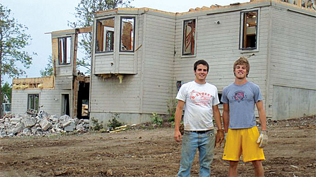 Sam and Parker Maher in front of a tornado-damaged home