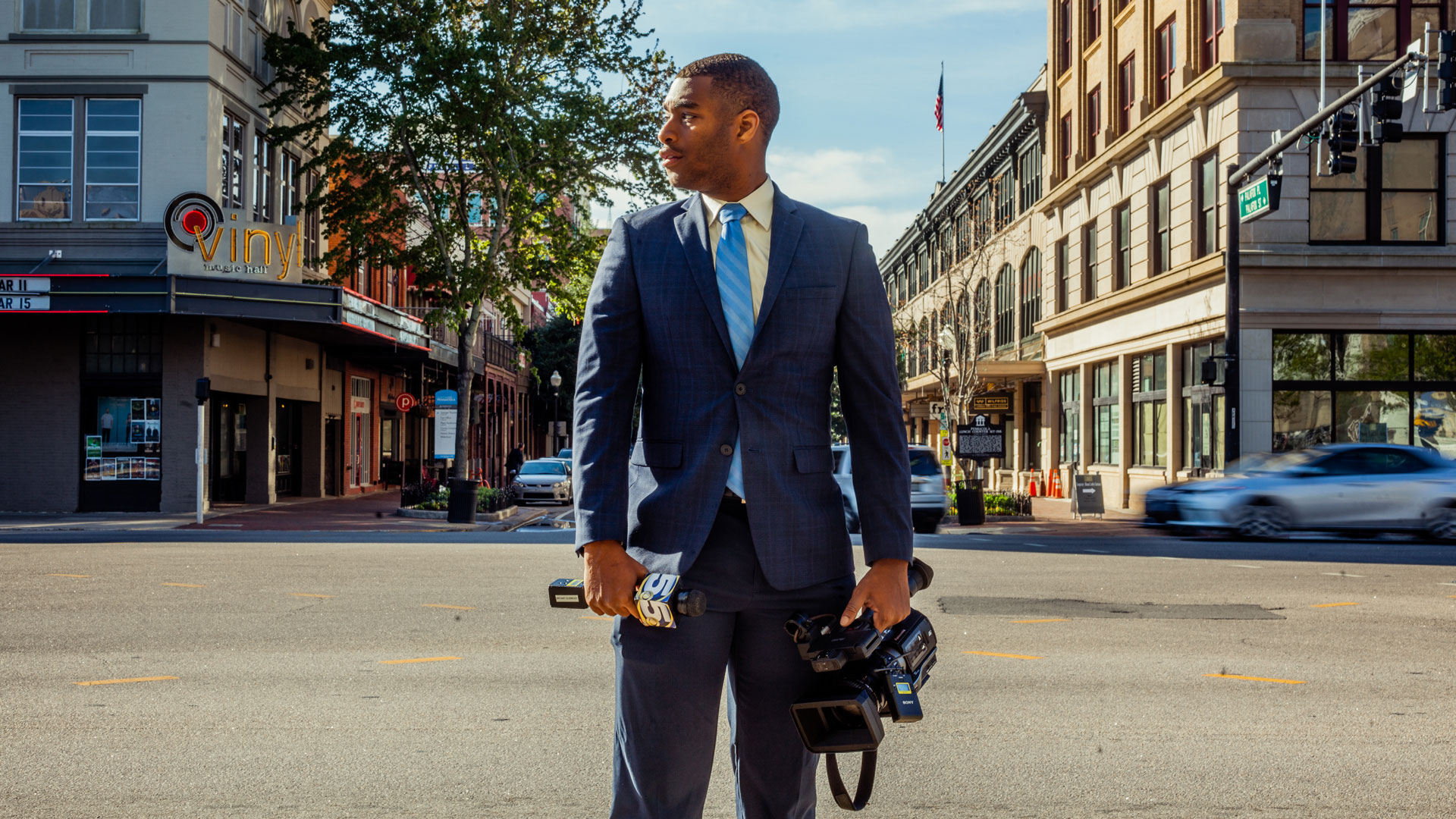 Bryant Clerkley stands in a street with his camera and microphone.