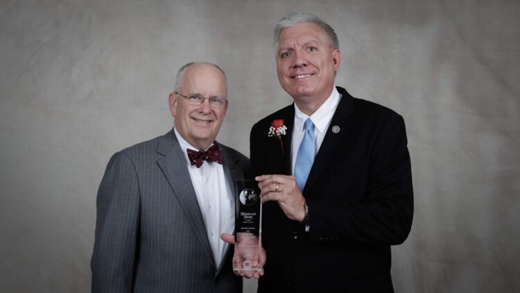 Randall Eggert holds his award with President Smart