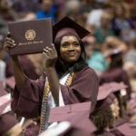 graduate holds up diploma