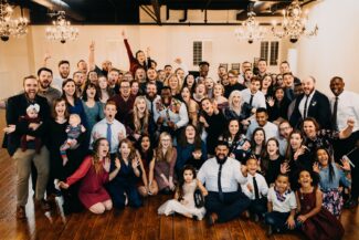 A wedding party poses around the couple at the reception
