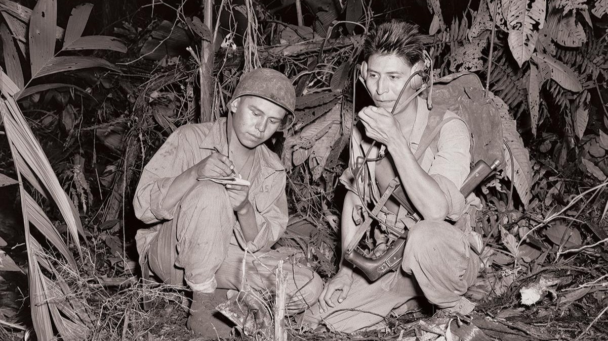 Navajo code talkers Corporal Henry Bahe Jr. (left) and Private First Class George H. Kirk (right) transmit over a portable radio in Bougainville in the South Pacific during December 1943.