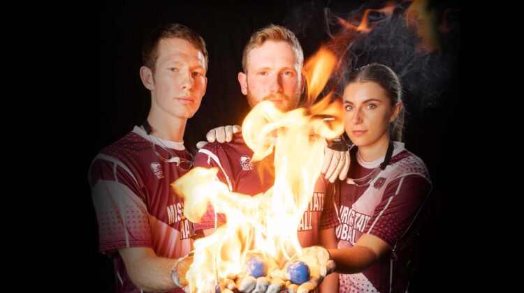 The MSU Handball team holds fiery handballs in their gloved hands.