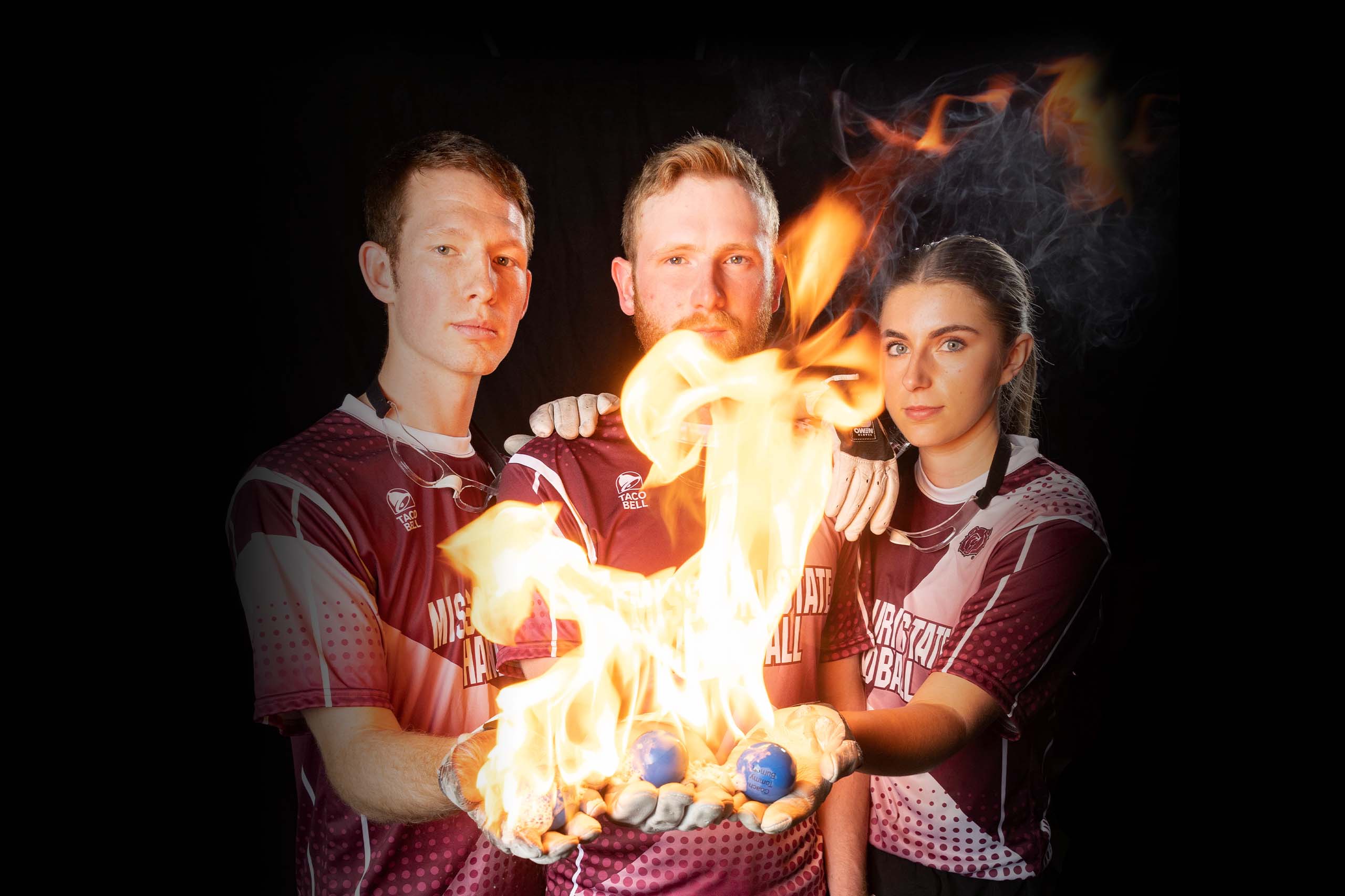 The MSU Handball team holds fiery handballs in their gloved hands.
