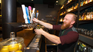 Bartender dispensing beer and smiling.