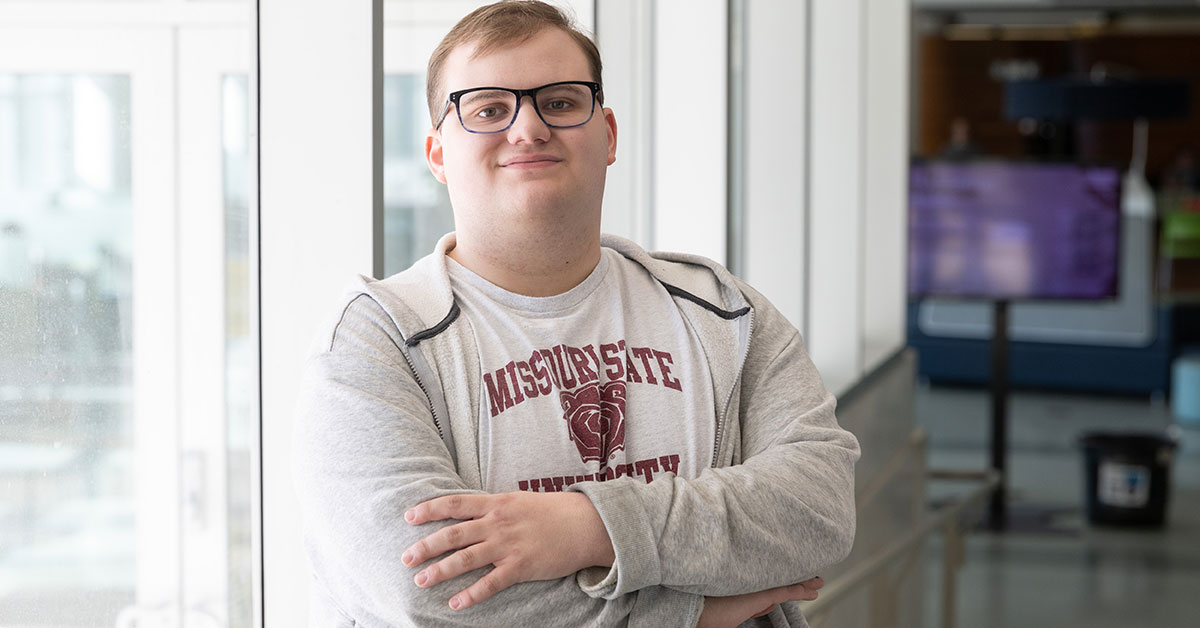Daniel Paige crosses his arms to pose for a picture in Meyer Library.