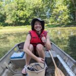 Daphne Miles on a small rowboat with a red life vest on smiling