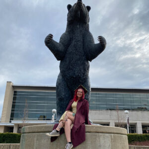 Abilene reclines in her graduation regalia next to the MSU Bear statue in front of the Plaster Student Union.