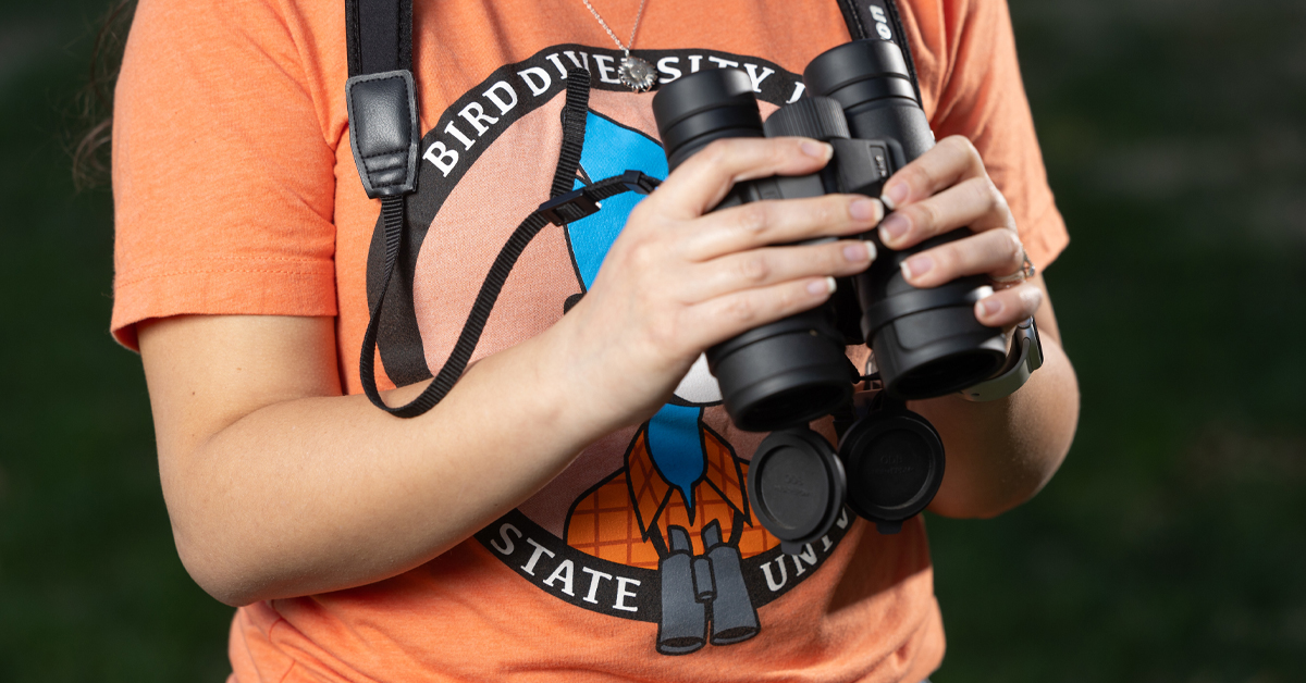 Carroll holds binoculars in her hands.