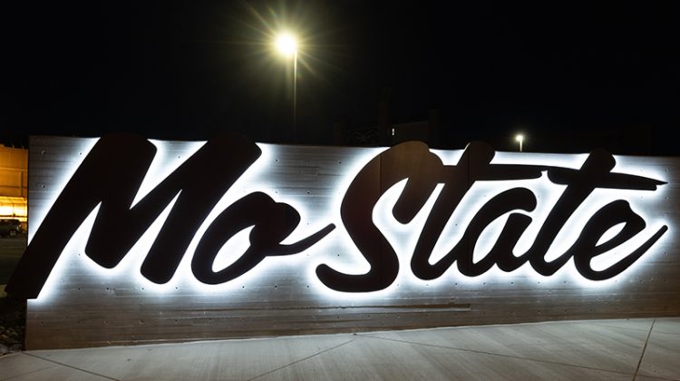 The Mo State sign on campus lighted up at night.