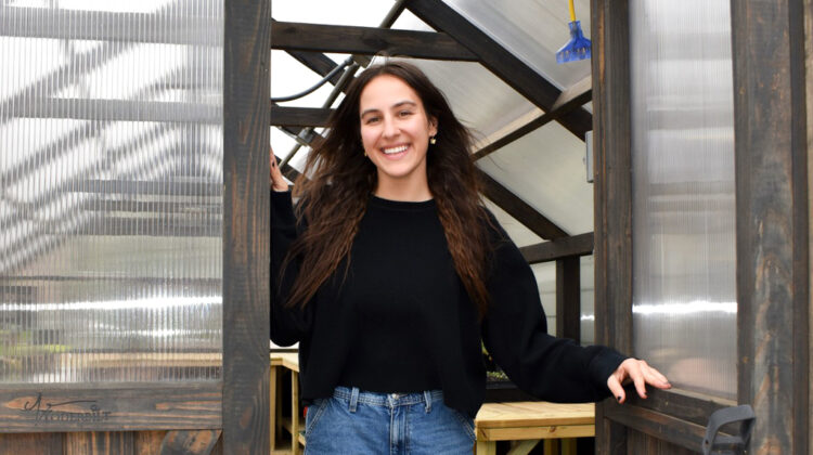 Amanda poses in the doorway of a garden greenhouse