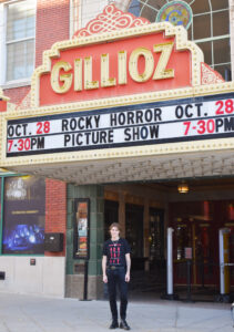 Adam stands in front of The Gillioz Theatre entrance and box office