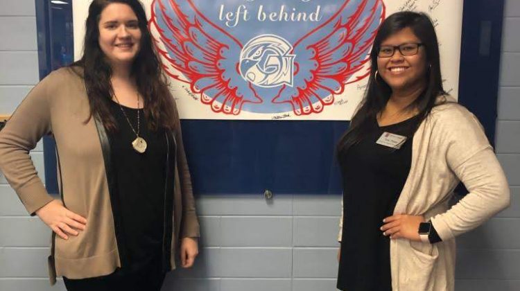 Kelsey Quick and Tina Pham stand in front of a "Flock Together" banner at Glendale High School