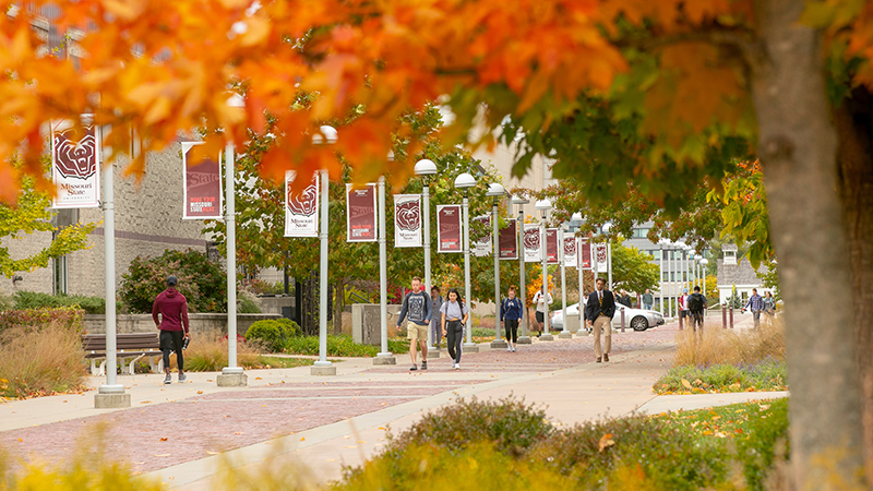 Students walk on campus on a beautiful fall day.