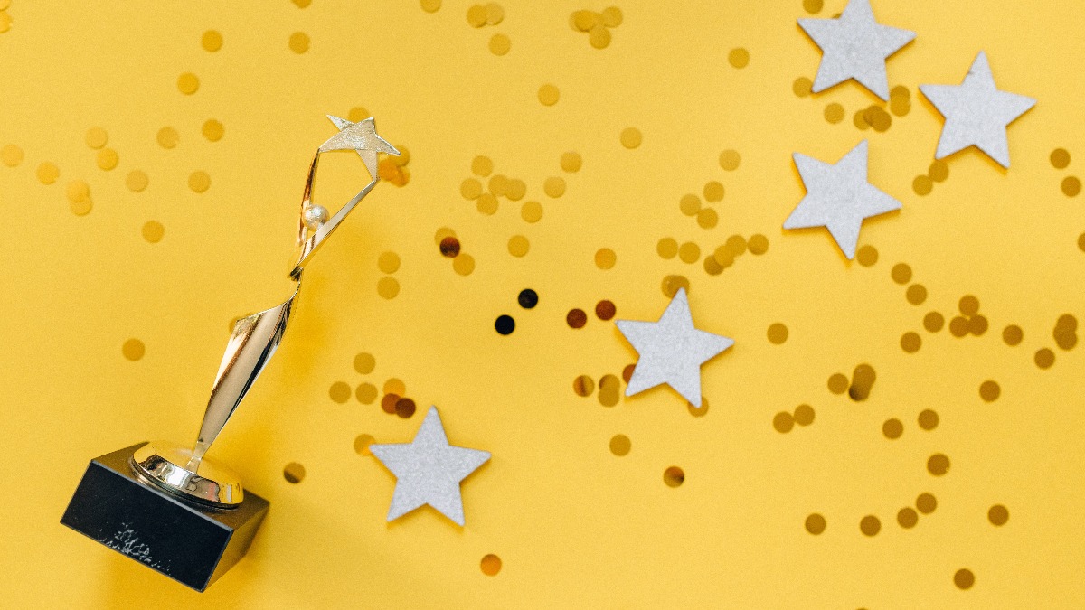 An award rests among star cut outs and glitter on a bright yellow backdrop.