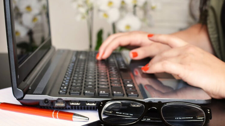 A woman types on the keyboard of her laptop.