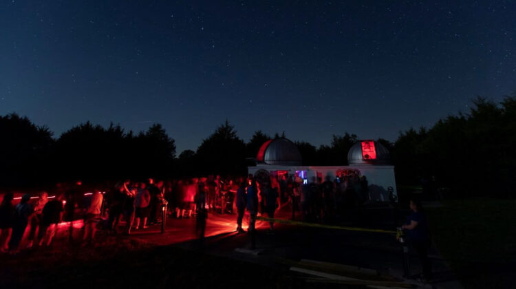 A nighttime view of Baker Observatory as a line forms outside of the viewing stations.