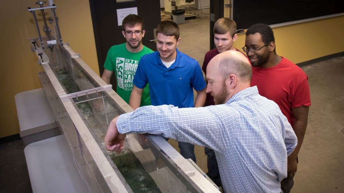 Dr. Matt Pierson shows a group of students how to operate a piece of engineering equipment.
