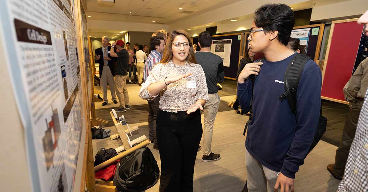 Ana Torres explaining her research poster to two students during the 2022 CNAS Ana Torres posing among the crowd at the 2022 CNAS Ana Torres posing among the crowd at the 2022 CNAS Undergraduate Research Symposium.
