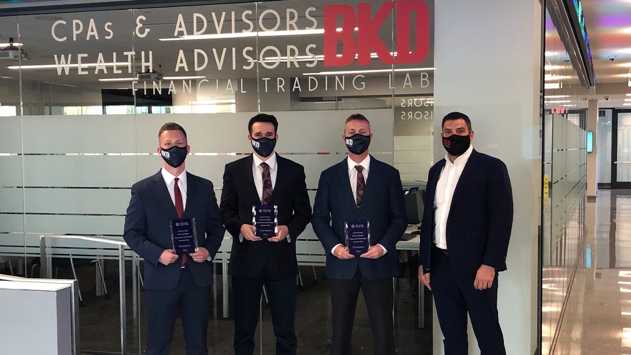 Four men with masks holding award plaques