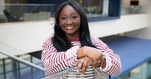 Kamryn Middleton smiling and leaning against the glass stairwell in Glass Hall.