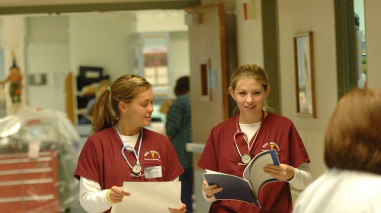 Nursing students in scrubs walk down a clinical hallway together